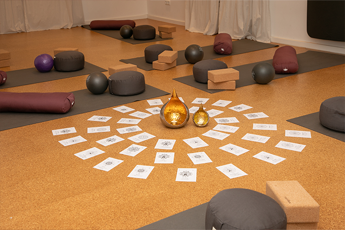 mehrere Yogamatten, Kissen, Bälle und Yogablöcke liegen in einem Raum.