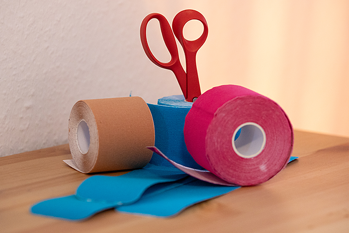 Kinesio Tapes für Taping in der Schwangerschaft bei Beschwerden wie Rückenschmerzen oder Rektusdiastase Eine Schere und Kinesio Tapes zum Tapen in der Schwangerschaft